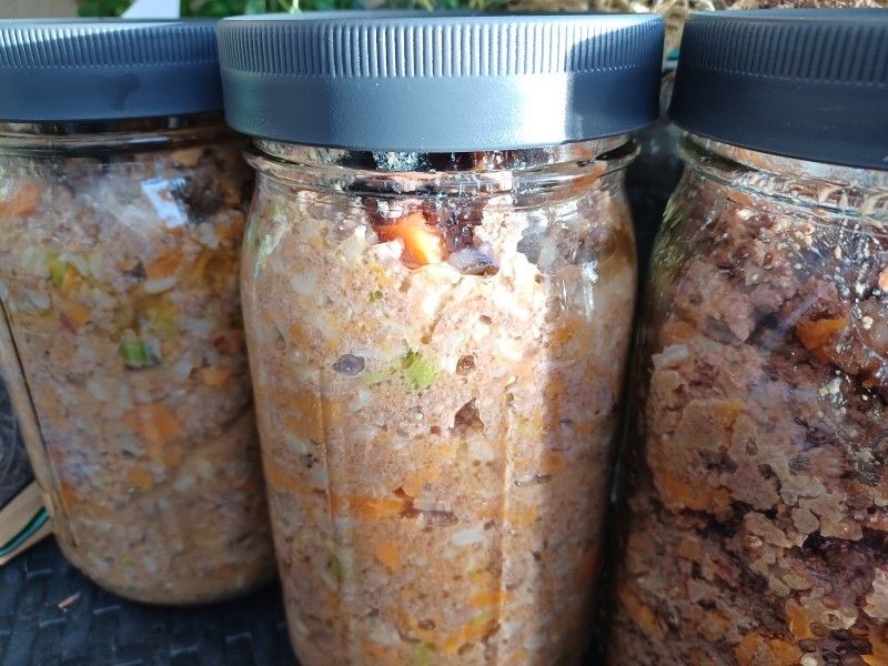 Three jars filled with homemade potted meat, sealed with gray lids, and displayed close together.